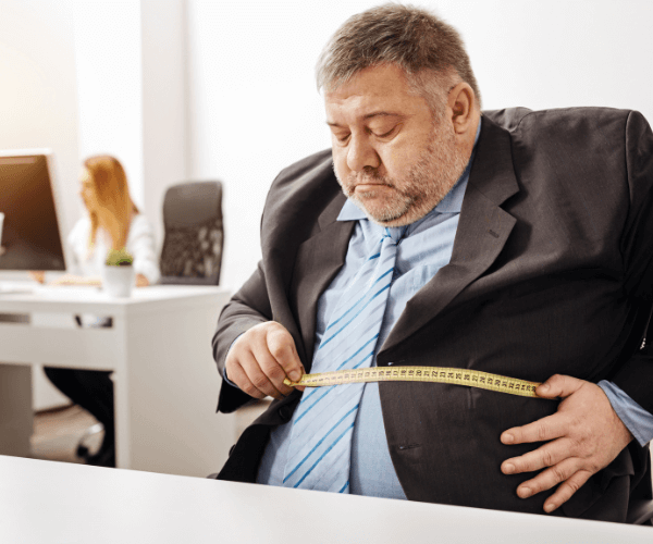 Overweight man at desk with tape measure
