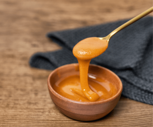 Manuka Honey Dipper Dipping in Raw Organic Liquid